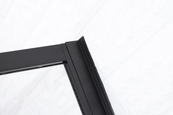 Close-up van de bovenkant van een zwarte douchedeur met een metalen frame