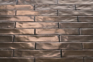 Close-up van rechthoekige, glanzende, bronzen tegels die in een baksteengewijs patroon zijn gerangschikt.