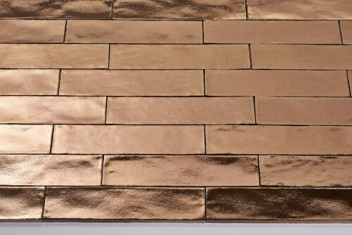 Bronzen glanzende tegels in baksteenpatroon.