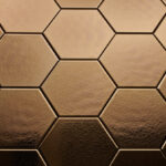 Wandtegel Hexagon Onda goud Close-up van zeshoekige, brons/ gouden tegels met een matte afwerking, gerangschikt in een honingraatpatroon.